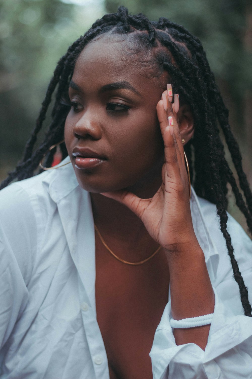 a woman with dreadlocks is holding her hand up to her ear