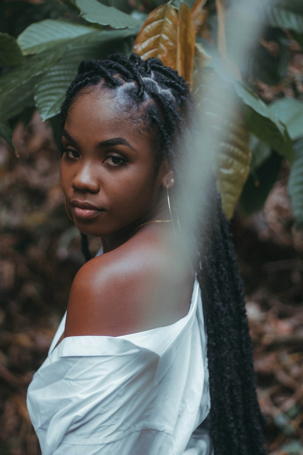 a woman with braids standing in front of a tree