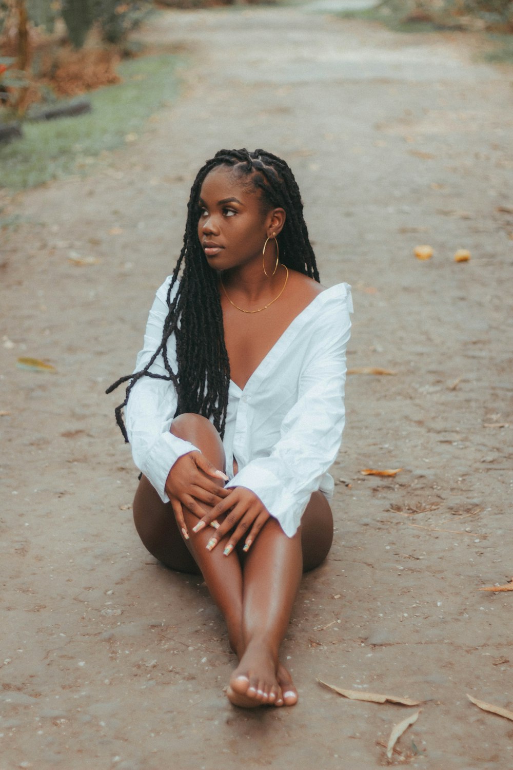 a woman sitting in the middle of a dirt road