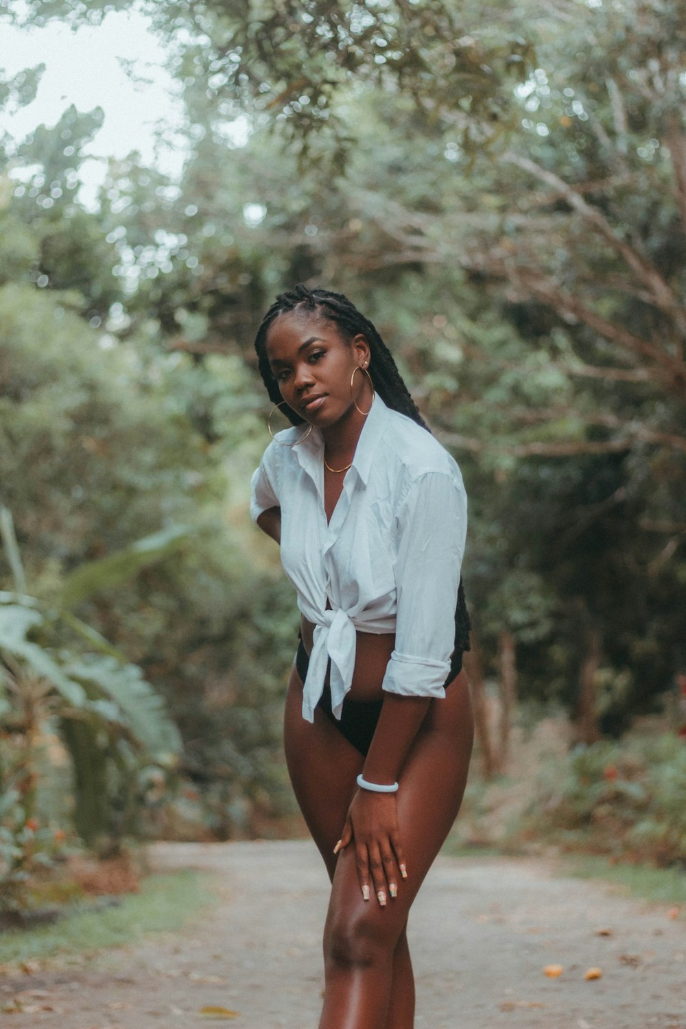 a woman in a white shirt and black shorts standing on a dirt road