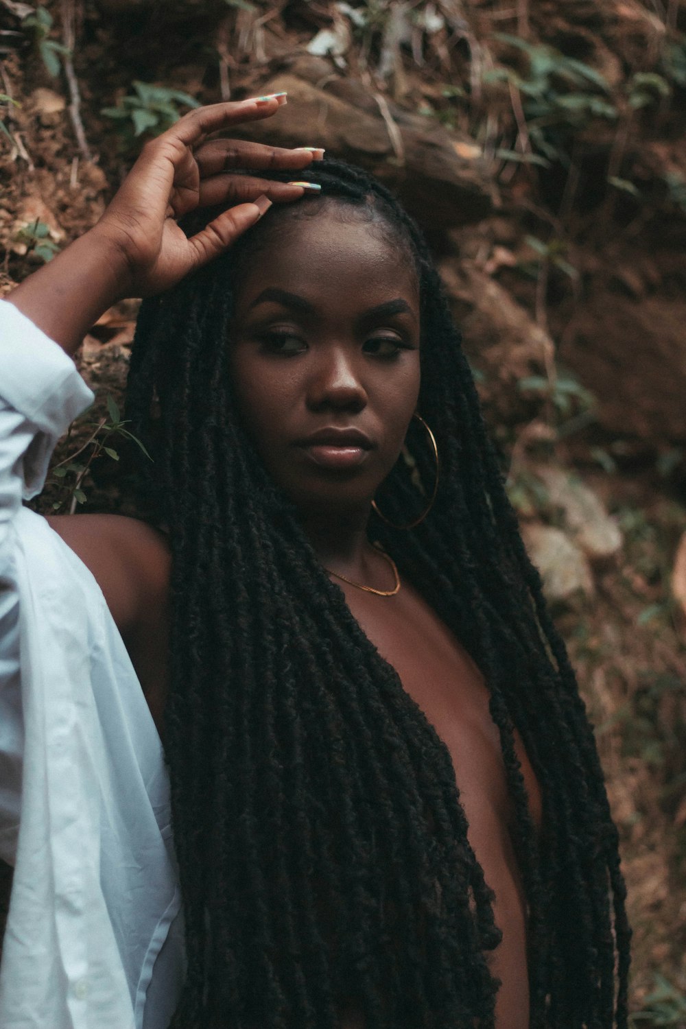 a woman with dreadlocks standing in the woods