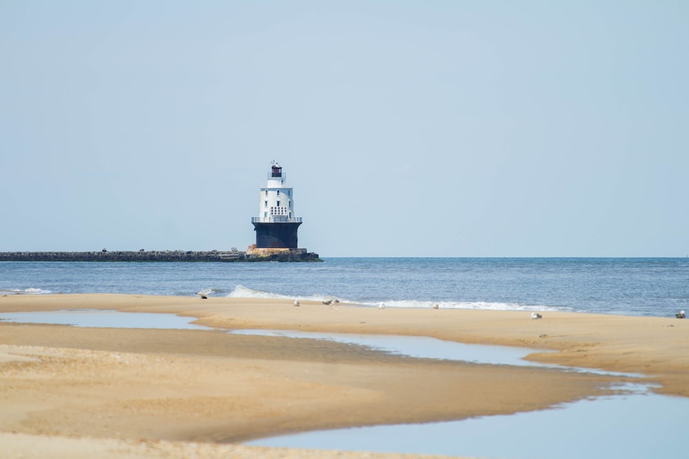 Un faro seduto sulla cima di una spiaggia vicino all'oceano