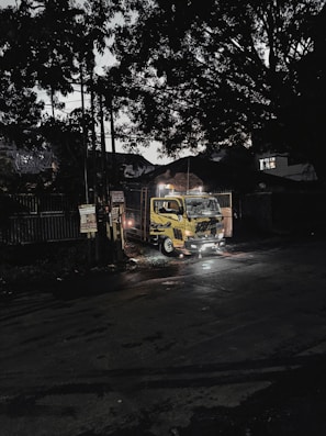 Blue and yellow transport truck parked in front of a Barcelona cityscape at dawn.
