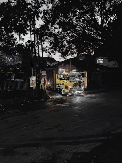 A sleek golden tow truck illuminated by soft glowing lights on a dark urban street at night