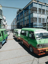 A fleet of Javaya transport vehicles lined up under a clear blue sky, showcasing various models from luxury Hiace to spacious buses.