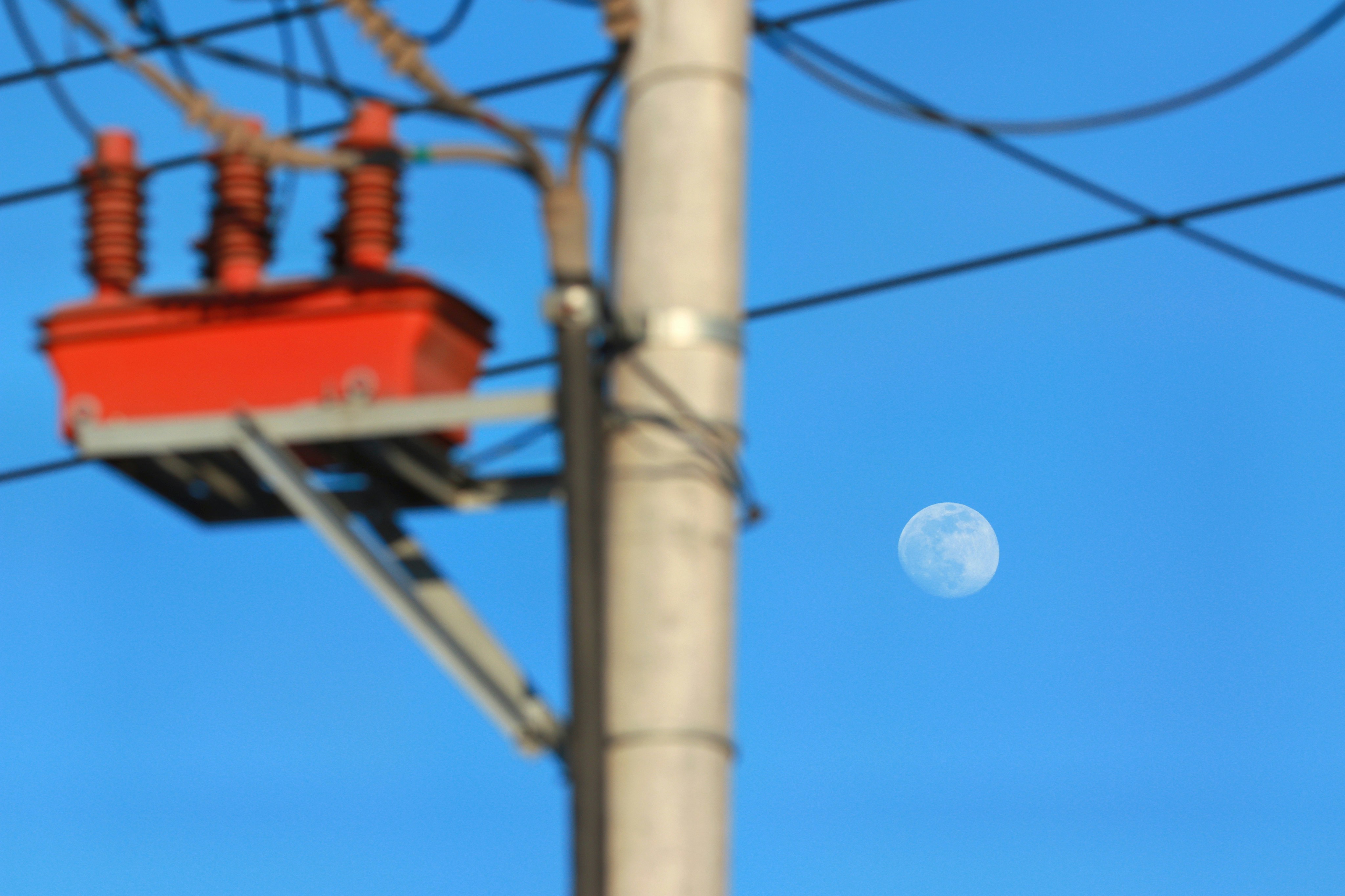 a telephone pole with wires and a full moon in the background