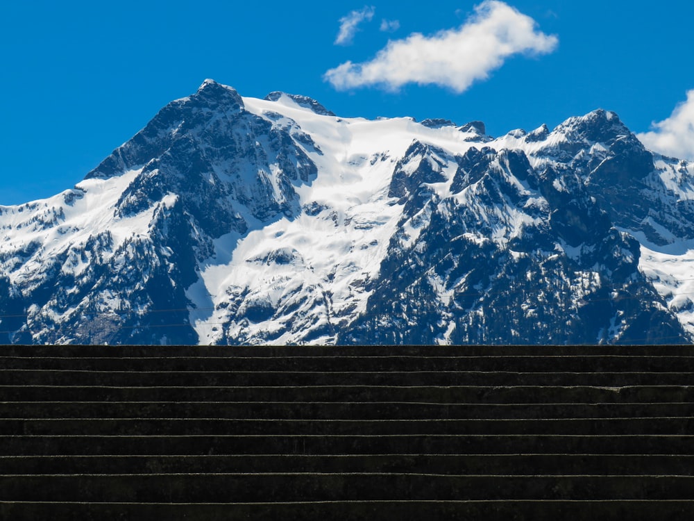 a person sitting on a bench in front of a mountain
