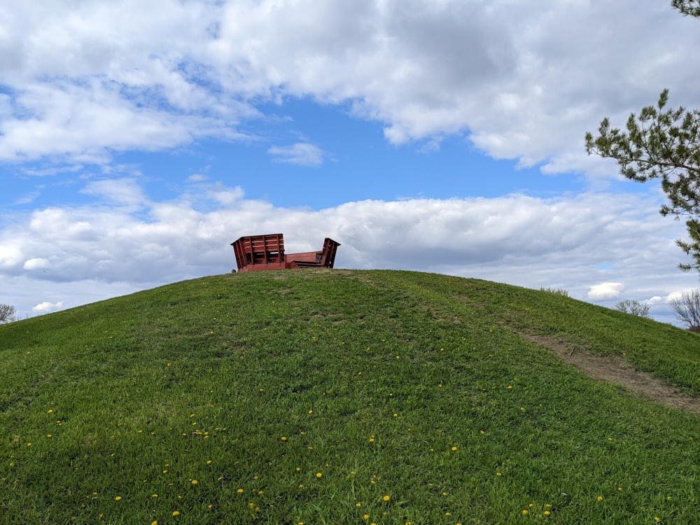 two wooden benches sitting on top of a green hill
