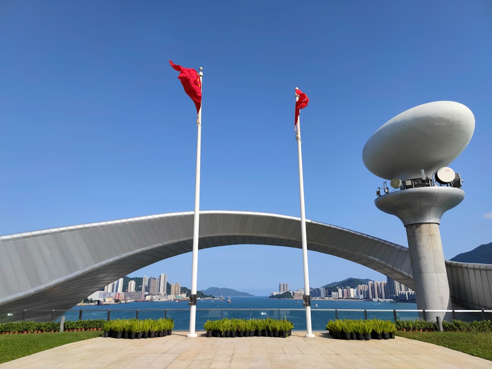 two red flags are on poles in front of a bridge