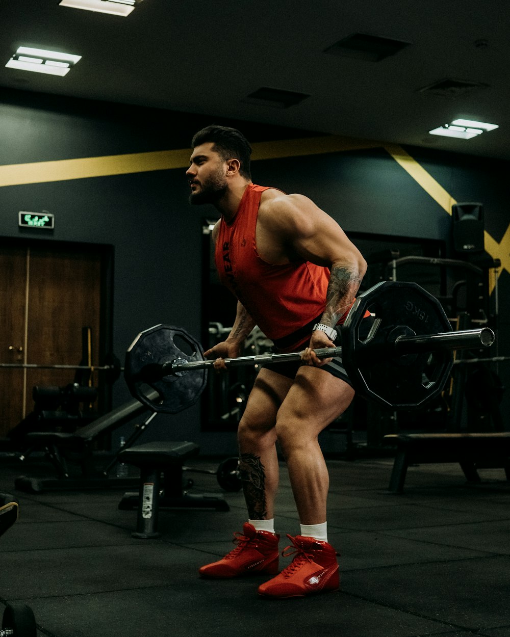 a man with a barbell squats in a gym