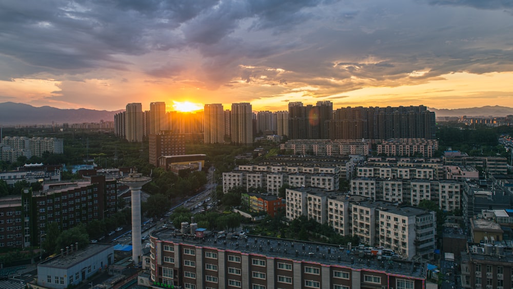 the sun is setting over a city with tall buildings