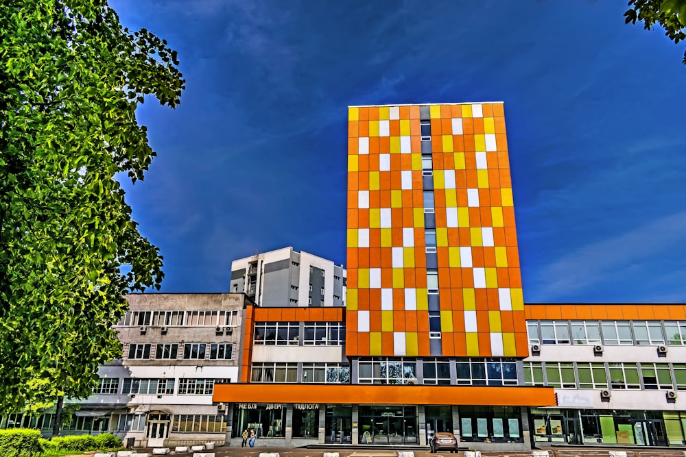 a tall orange building sitting next to a lush green forest