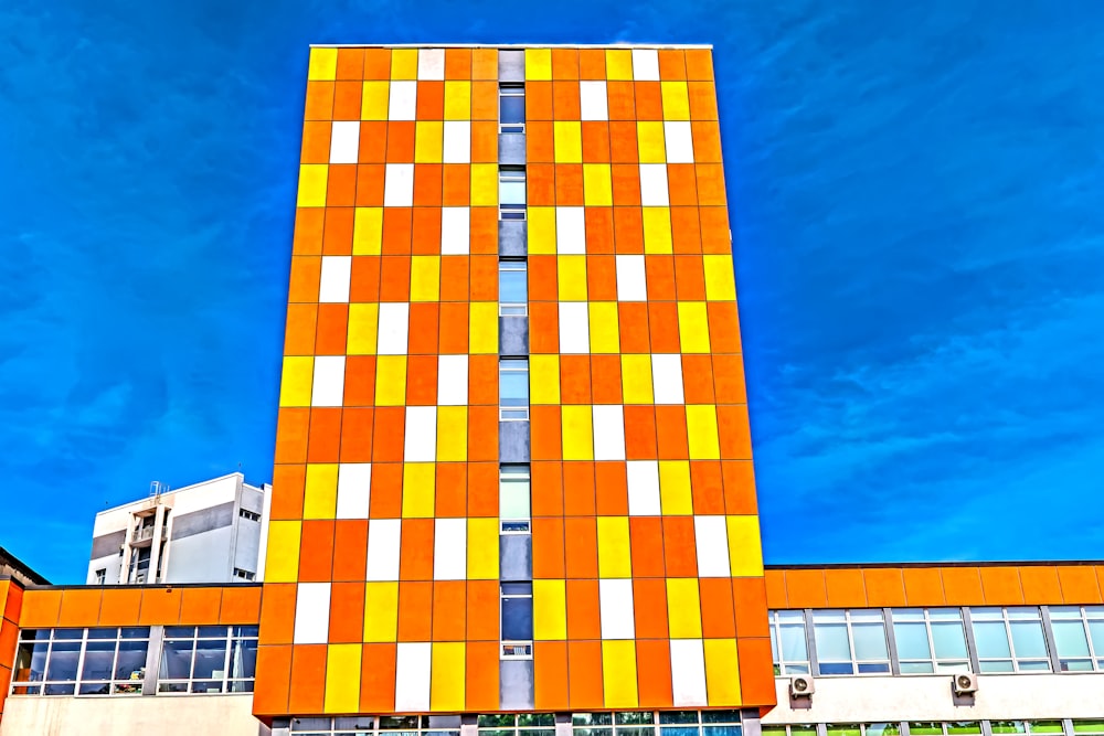 a tall orange and white building with a blue sky in the background