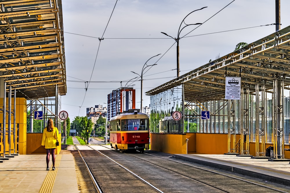 um trem vermelho e amarelo puxando para uma estação de trem