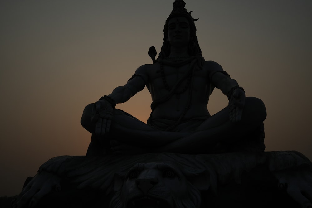 a statue of a person sitting in the middle of a body of water