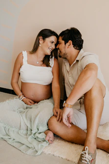 a pregnant couple sitting on the floor together