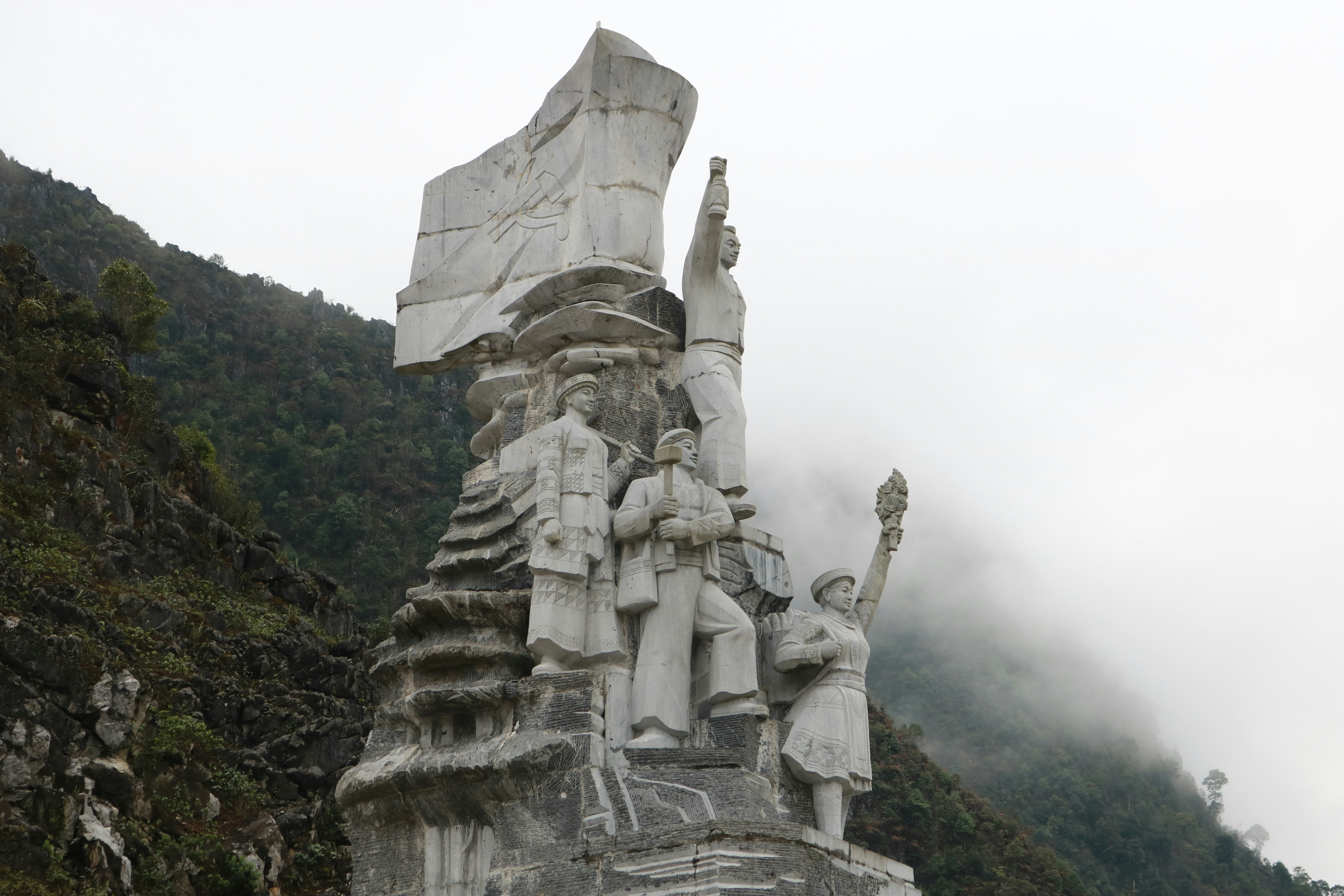 a statue of a group of people in front of a mountain