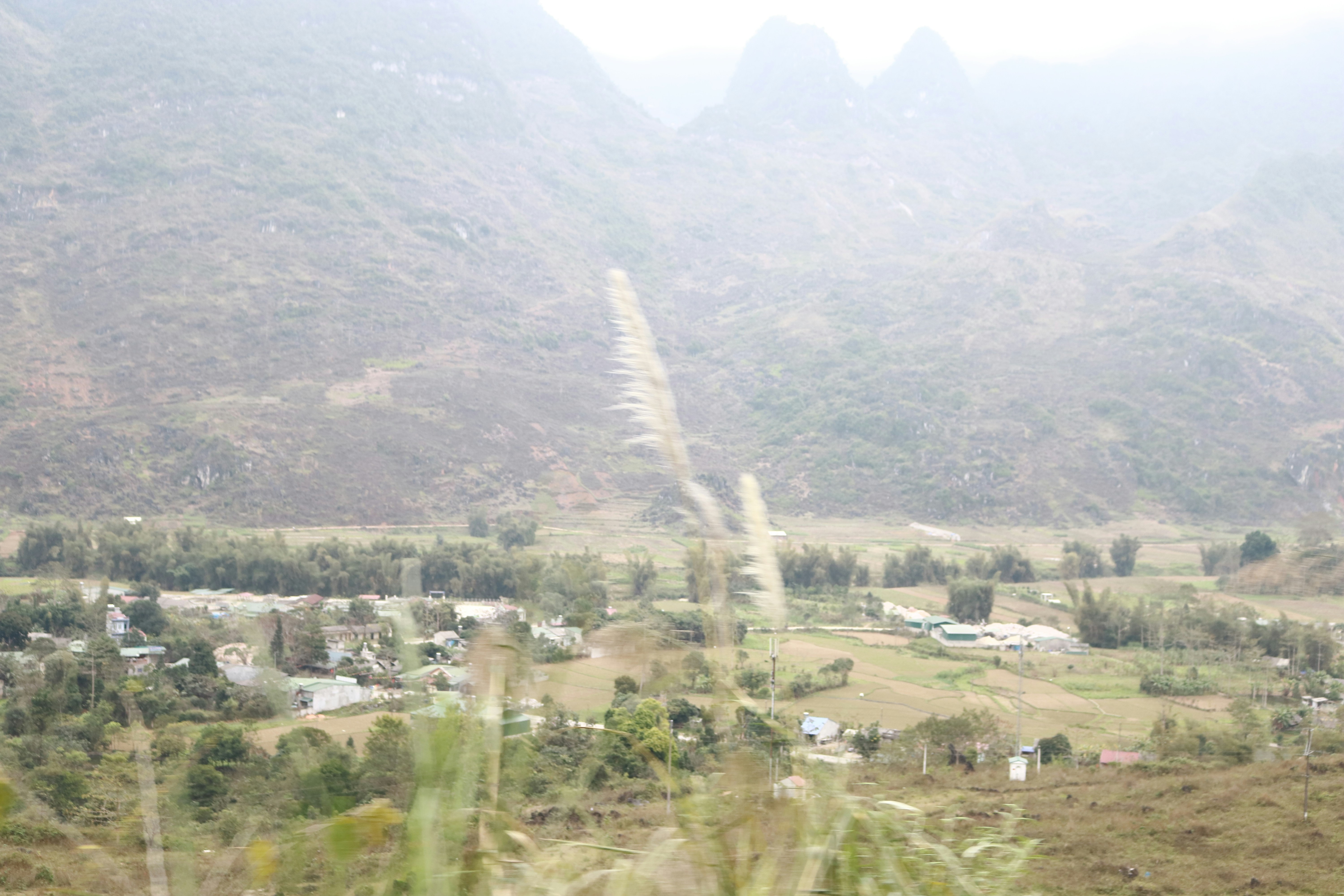 a view of a village in a valley with mountains in the background
