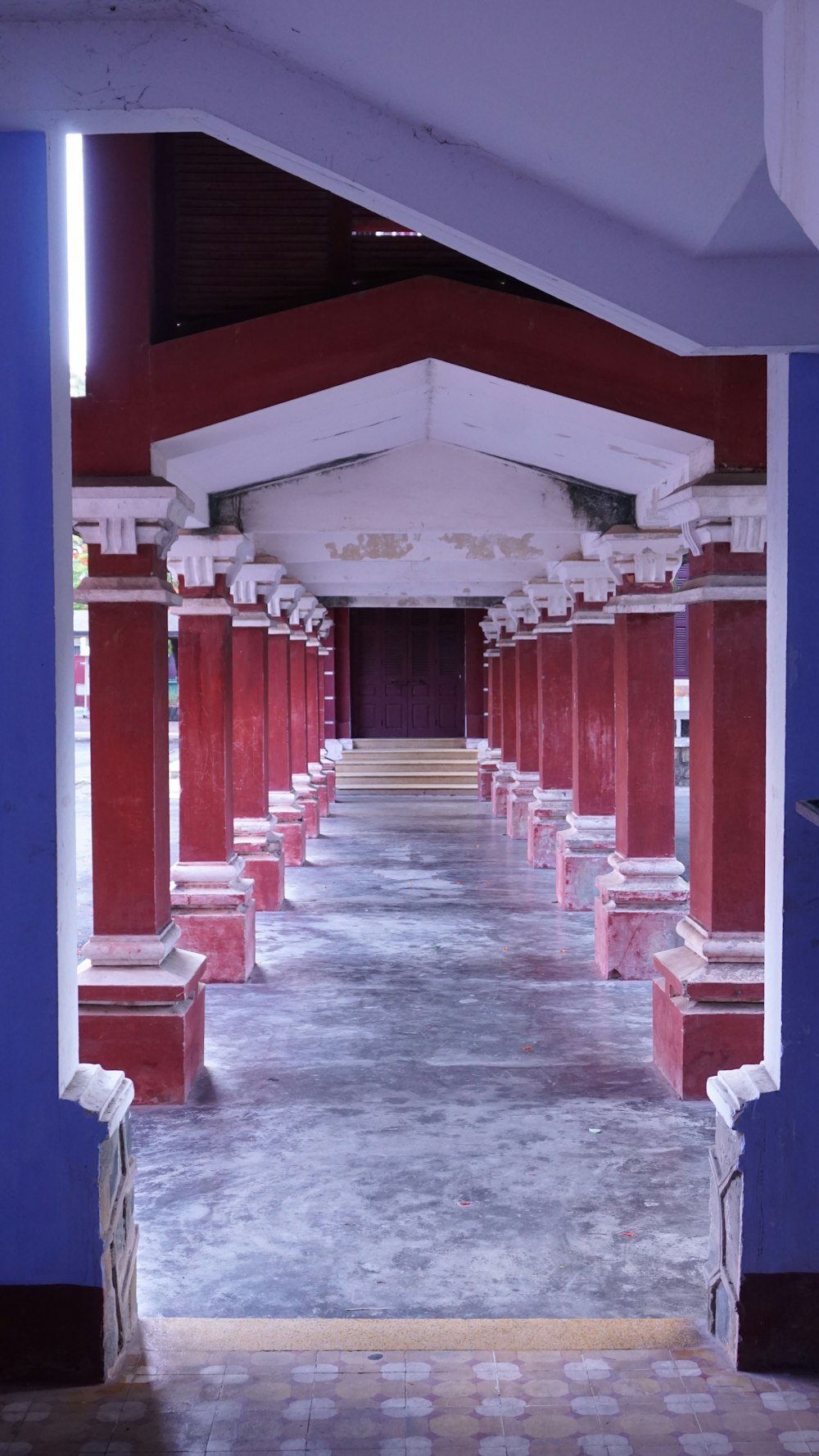a long hallway with red pillars and blue walls