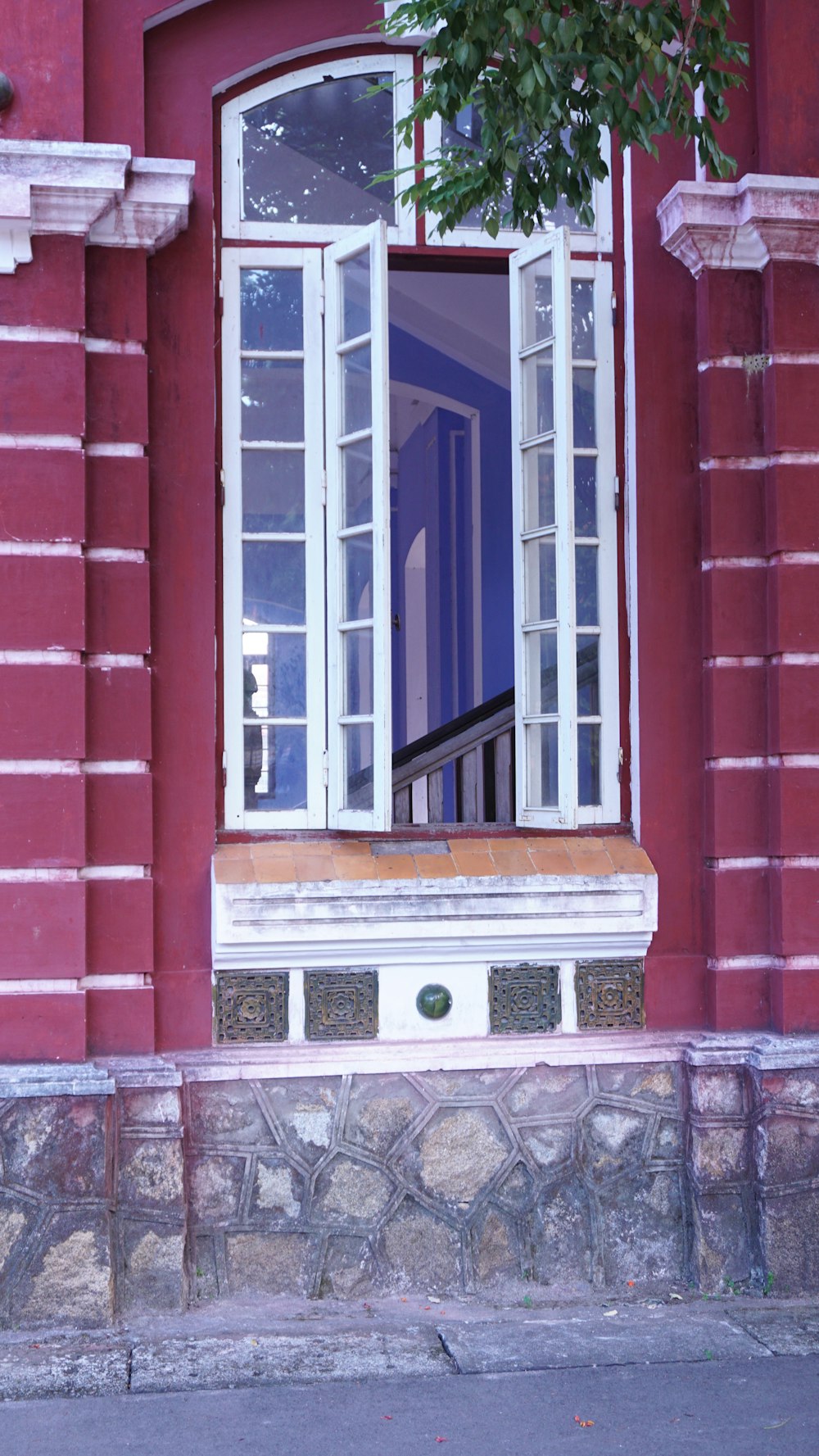 a red building with a window and a bench in front of it