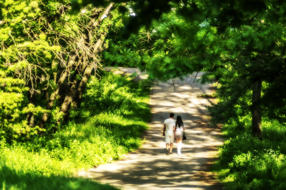 a couple of people walking down a dirt road