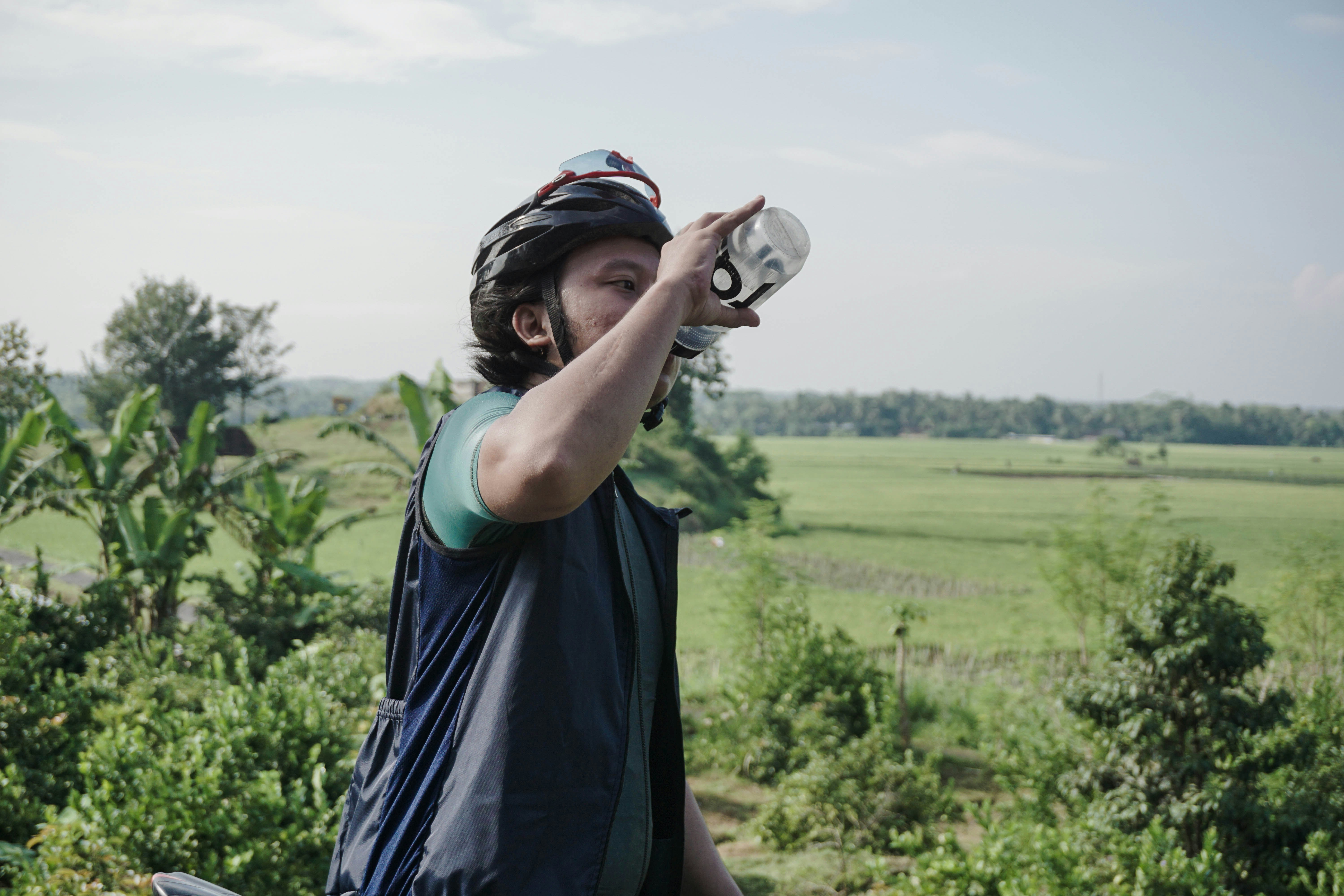 Seorang pria yang mengenakan helm sedang minum dari botol