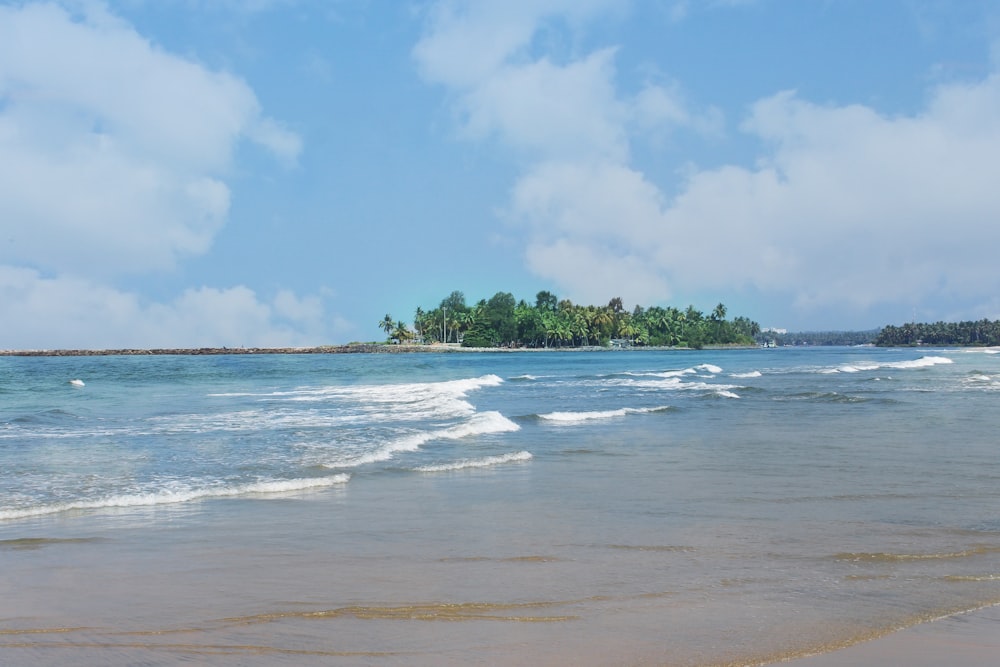 a sandy beach with a small island in the distance