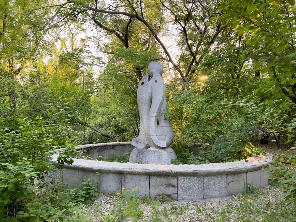 Una estatua en medio de un parque rodeado de árboles