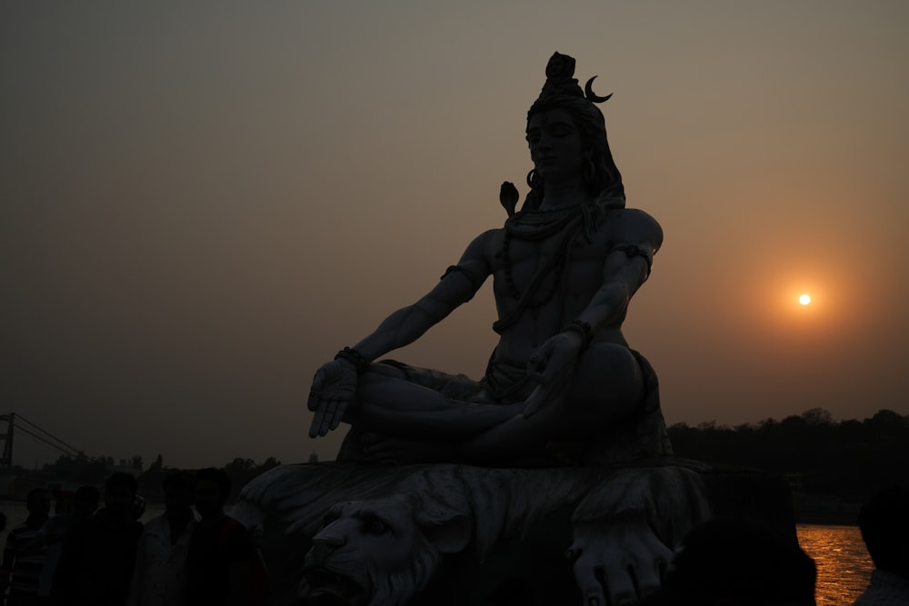 a statue of a woman sitting on top of a body of water