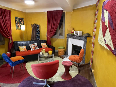 A warm, inviting living room with rich red and yellow accents, showcasing a cozy media wall and elegant shelving.