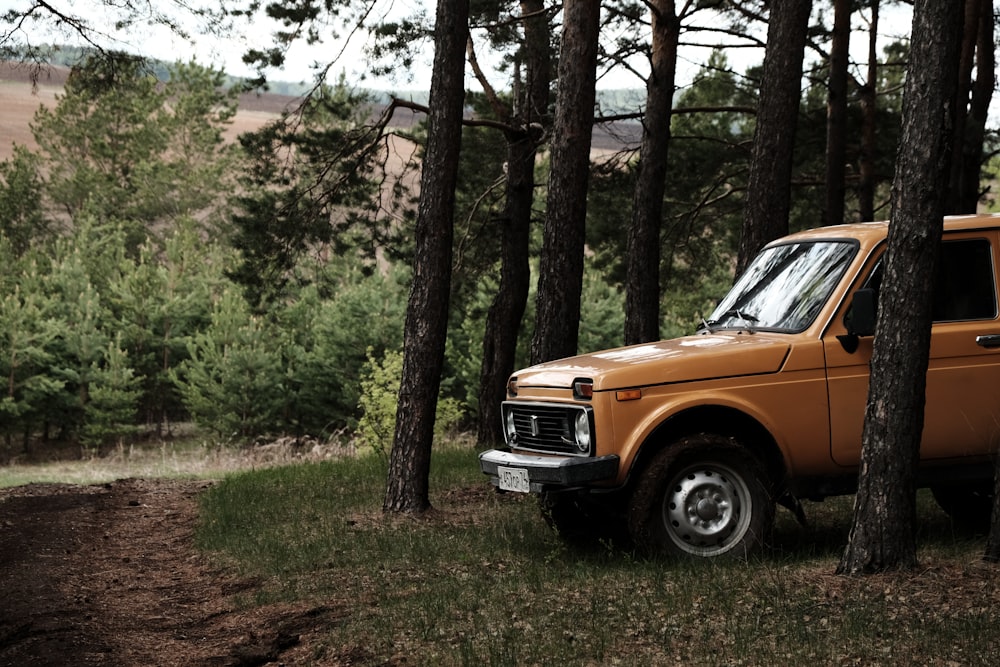 an orange truck parked in the middle of a forest