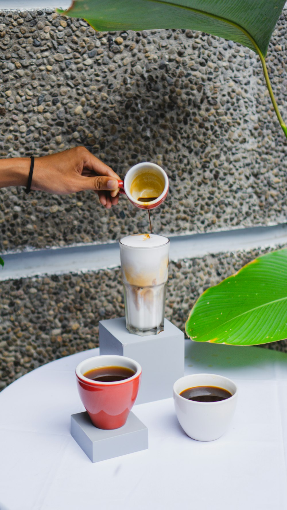 a person pours a cup of coffee into two cups