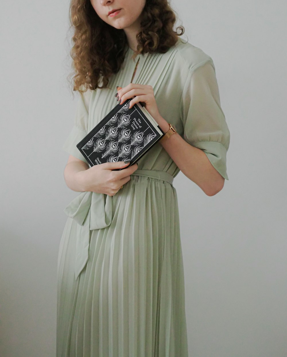 a woman in a green dress holding a book
