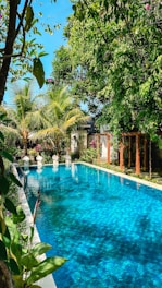 a large swimming pool surrounded by lush green trees