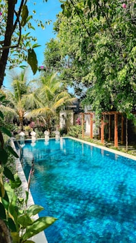 a large swimming pool surrounded by lush green trees