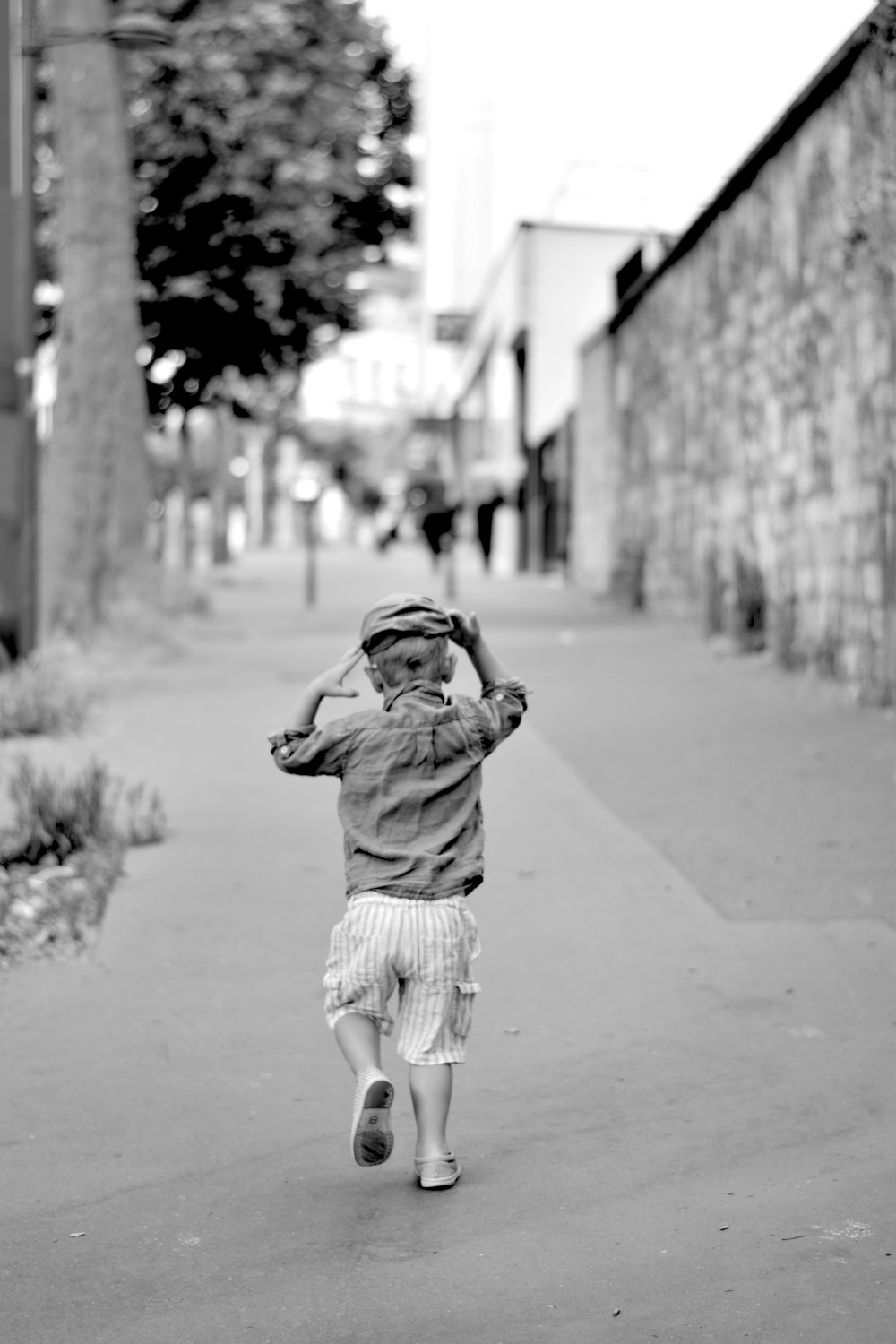 a young boy walking down a sidewalk next to a building