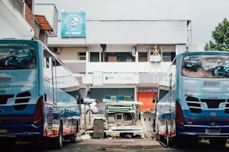 A fleet of well-maintained buses and trucks parked in front of a company building.