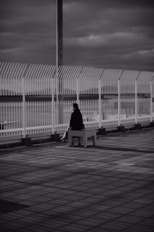 a black and white photo of a person sitting on a bench