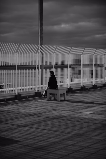 a black and white photo of a person sitting on a bench
