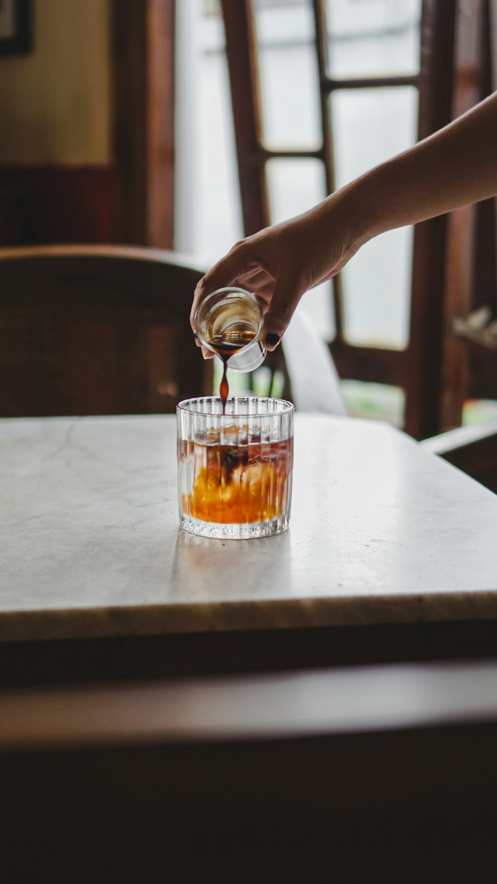 a person pours tea into a glass on a table