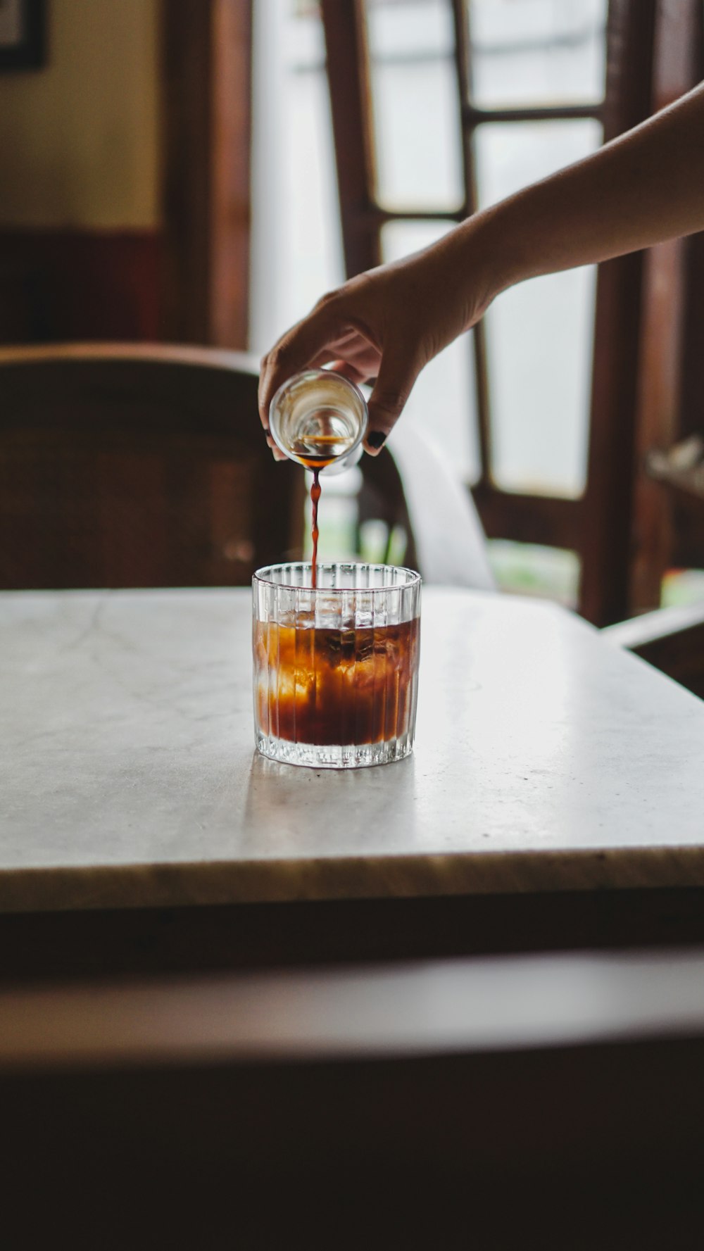 a person pours syrup into a glass on a table