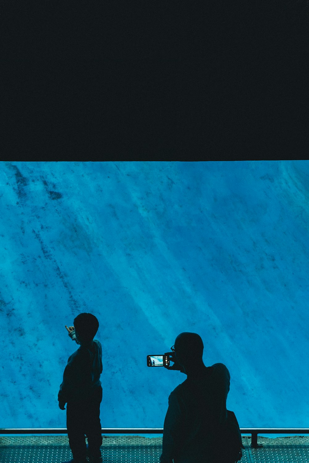 a couple of people standing in front of a blue wall