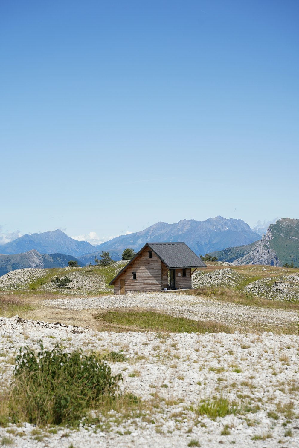 a small cabin in a field with mountains in the background