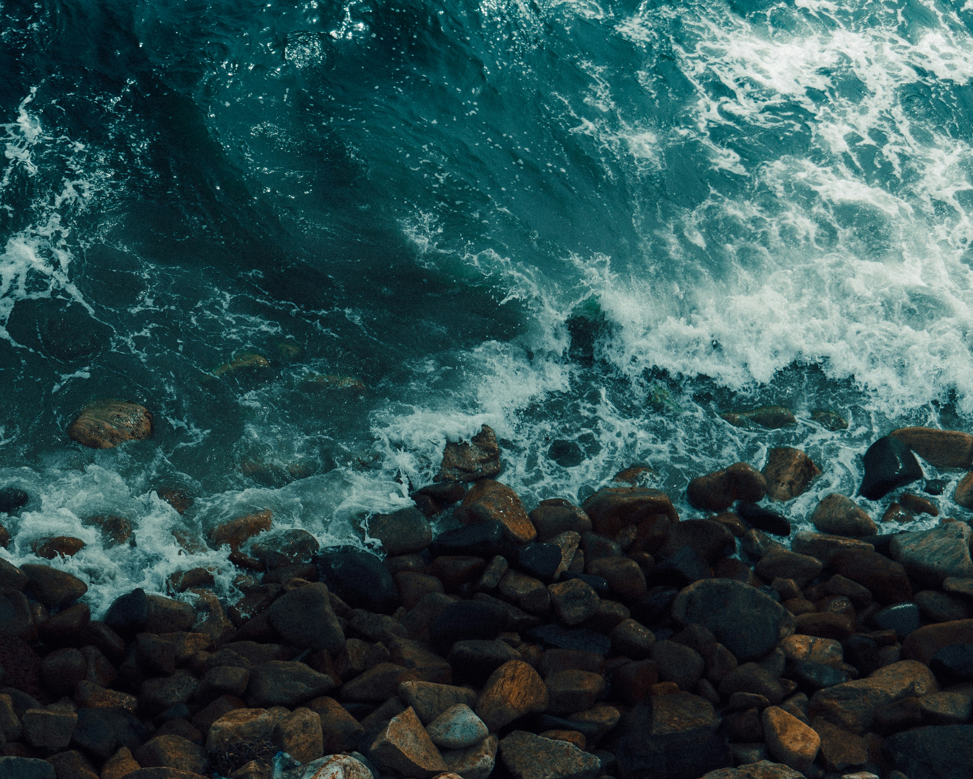 an aerial view of the ocean and rocks