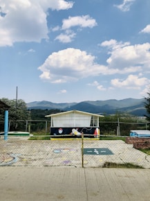 a fenced in area with a building and mountains in the background