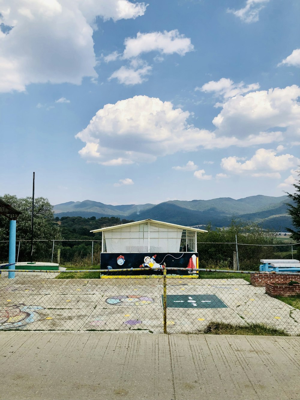 a fenced in area with a building and mountains in the background