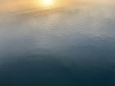An image of a calm Idaho river reflecting the soft peacock blue sky at dawn, embodying hope and sincerity.
