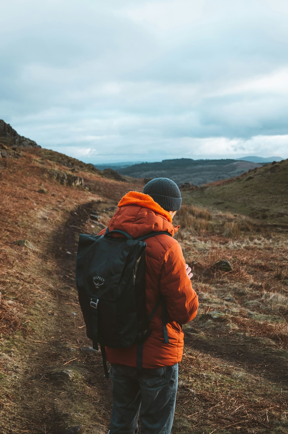 Eine Person mit einem Rucksack geht einen Hügel hinauf