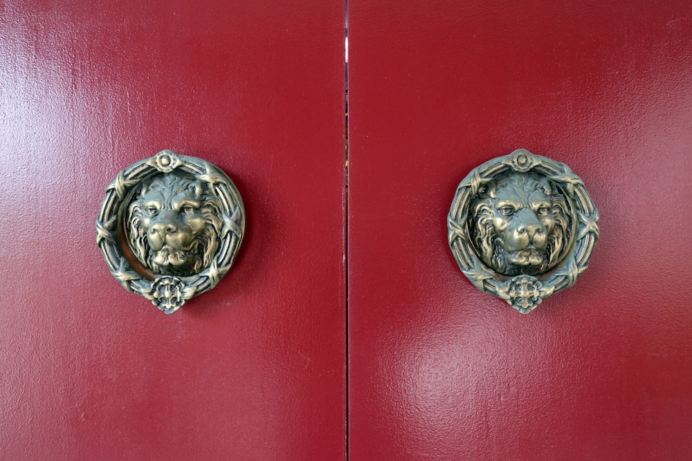 una puerta roja con dos cabezas de león de metal