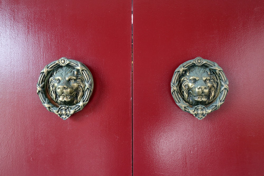 a red door with two metal lion heads on it